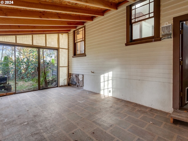 unfurnished living room with beam ceiling and wooden walls