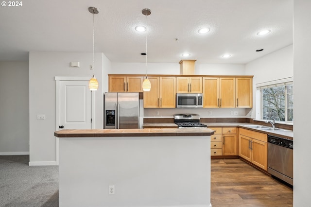 kitchen with light brown cabinets, sink, hanging light fixtures, and appliances with stainless steel finishes