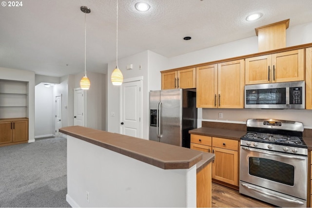 kitchen with pendant lighting, light carpet, appliances with stainless steel finishes, and a textured ceiling