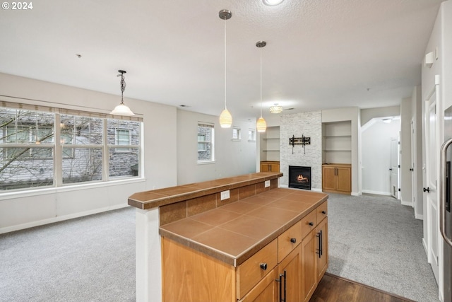 kitchen featuring pendant lighting, built in features, a fireplace, and carpet floors