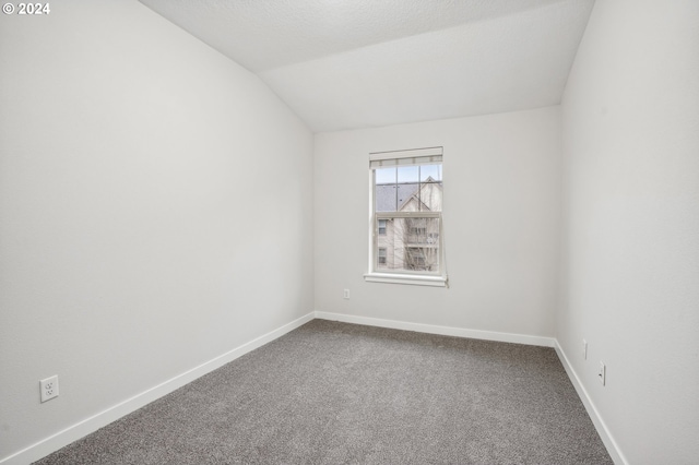 carpeted spare room with vaulted ceiling