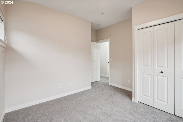 unfurnished bedroom featuring a closet and light colored carpet