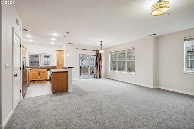 kitchen featuring kitchen peninsula, light carpet, a kitchen island, and hanging light fixtures