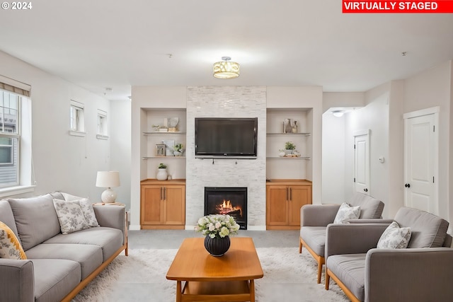 carpeted living room featuring built in shelves and a fireplace