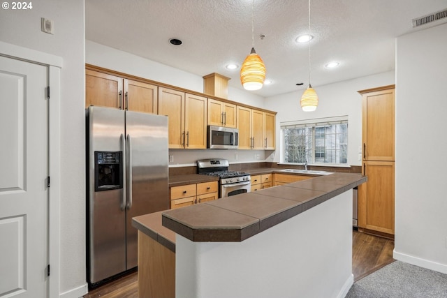 kitchen with appliances with stainless steel finishes, a textured ceiling, sink, a center island, and hanging light fixtures