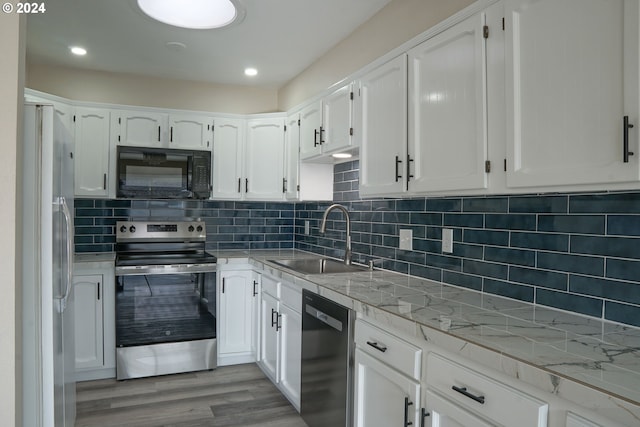 kitchen featuring white cabinetry, black appliances, sink, and light wood-type flooring