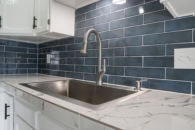 kitchen with sink, light stone countertops, decorative backsplash, and white cabinets