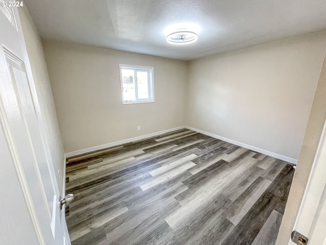 unfurnished room with hardwood / wood-style flooring and a textured ceiling