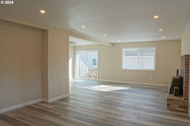 unfurnished living room with a textured ceiling and dark hardwood / wood-style flooring