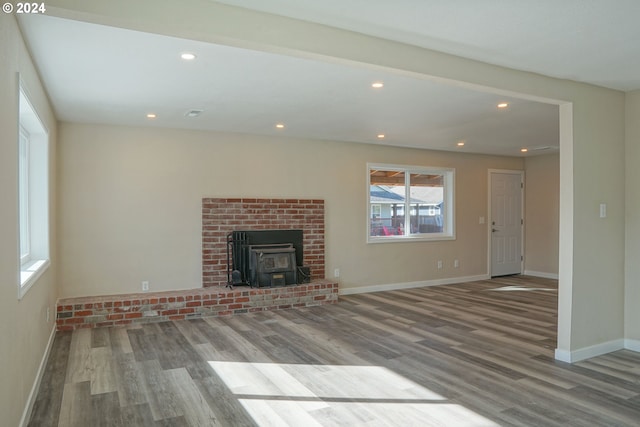 unfurnished living room with hardwood / wood-style flooring and a wood stove