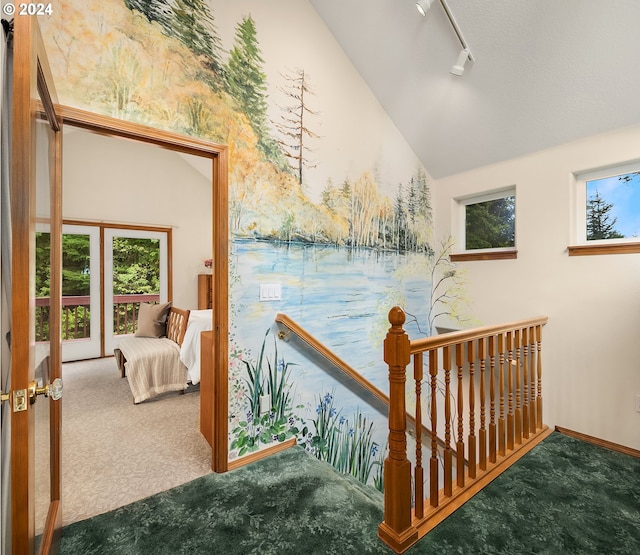 hall featuring carpet, french doors, rail lighting, and vaulted ceiling