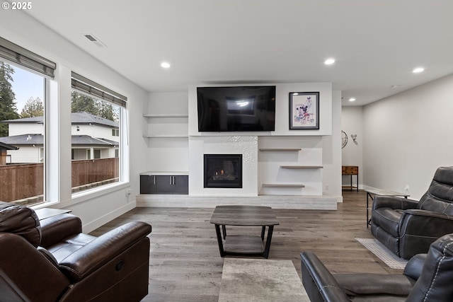 living area with light wood finished floors, recessed lighting, baseboards, and a glass covered fireplace