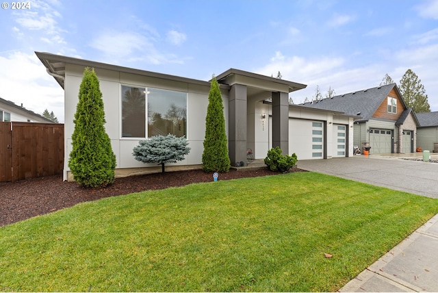 view of front facade featuring driveway, an attached garage, fence, and a front yard