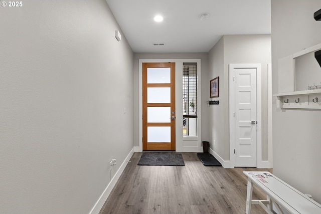 doorway featuring light wood finished floors, visible vents, and baseboards