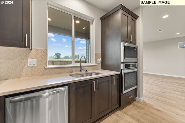 kitchen featuring backsplash, sink, appliances with stainless steel finishes, light hardwood / wood-style floors, and dark brown cabinetry