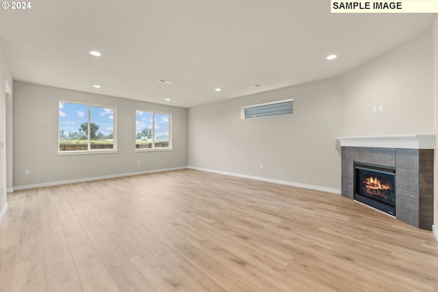 unfurnished living room featuring a tile fireplace and light hardwood / wood-style floors