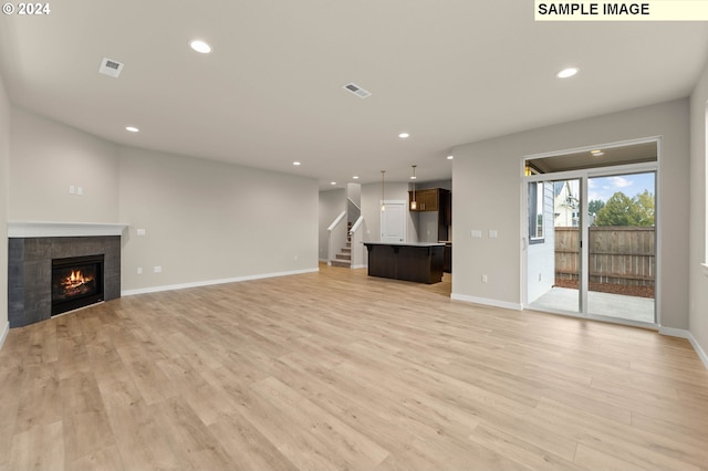 unfurnished living room featuring a tiled fireplace and light hardwood / wood-style flooring