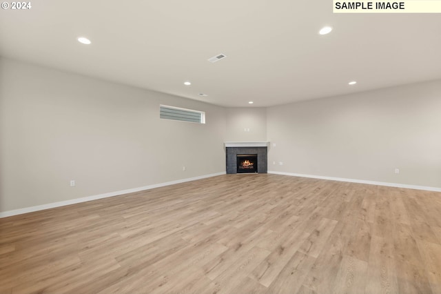 unfurnished living room featuring a tile fireplace and light hardwood / wood-style flooring