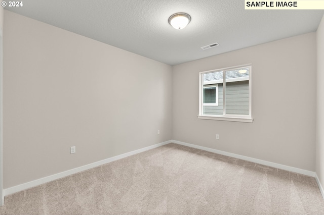 carpeted empty room with a textured ceiling