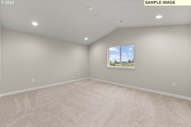 spare room featuring light carpet and lofted ceiling