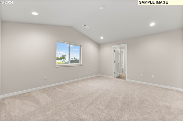 unfurnished room with light colored carpet and lofted ceiling