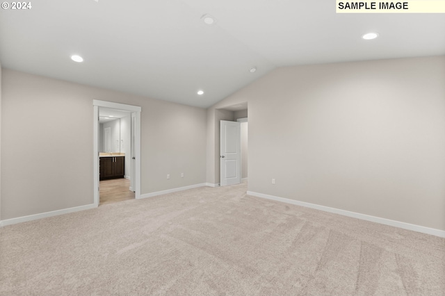 carpeted spare room featuring vaulted ceiling