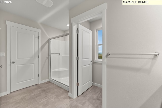 bathroom with hardwood / wood-style flooring and a shower with shower door