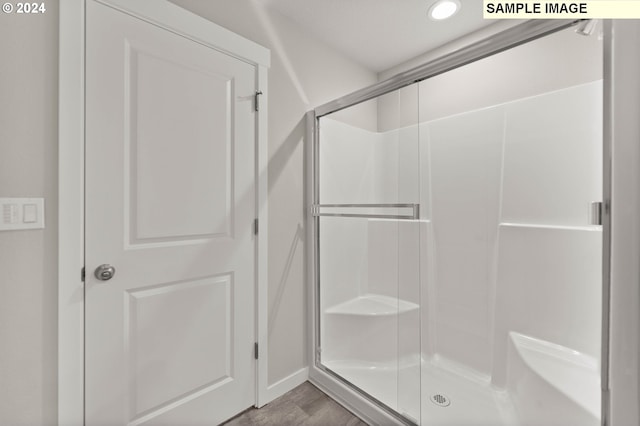 bathroom featuring wood-type flooring and a shower with door