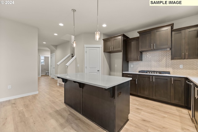 kitchen with stainless steel gas cooktop, light hardwood / wood-style floors, decorative light fixtures, a kitchen bar, and a kitchen island