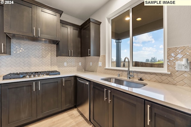 kitchen featuring sink, tasteful backsplash, light hardwood / wood-style floors, dark brown cabinets, and appliances with stainless steel finishes