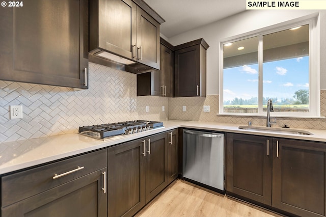 kitchen featuring sink, light wood-type flooring, backsplash, and appliances with stainless steel finishes