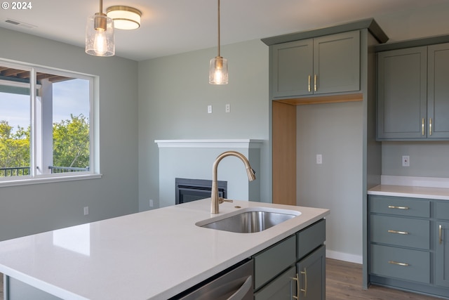 kitchen featuring light countertops, dark wood finished floors, dishwasher, a sink, and hanging light fixtures
