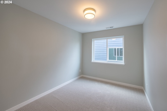spare room with visible vents, baseboards, and light colored carpet