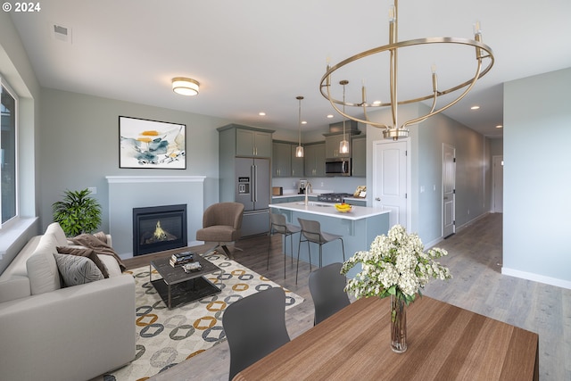 dining space featuring sink, light hardwood / wood-style flooring, and a notable chandelier