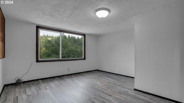 unfurnished room with a textured ceiling and light hardwood / wood-style floors