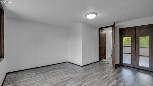 spare room featuring light wood-type flooring, a textured ceiling, and french doors