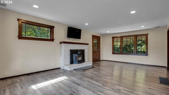 unfurnished living room featuring a fireplace, light wood-type flooring, and a healthy amount of sunlight