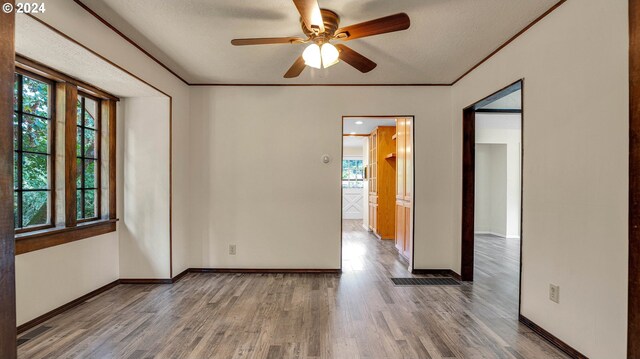 empty room featuring a textured ceiling, ornamental molding, hardwood / wood-style floors, and ceiling fan