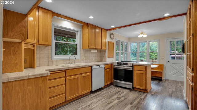 kitchen featuring kitchen peninsula, stainless steel stove, white dishwasher, tile countertops, and light hardwood / wood-style flooring