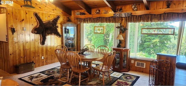 dining room with beam ceiling, wooden walls, carpet floors, and wooden ceiling