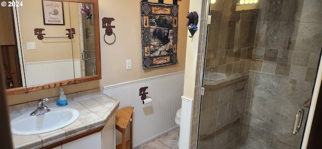 bathroom featuring tile patterned flooring, vanity, toilet, and walk in shower