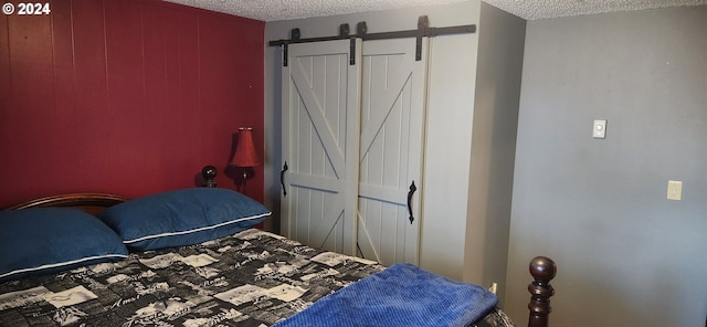 bedroom with a barn door, a textured ceiling, and a closet