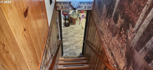 staircase featuring wooden walls