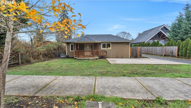 back of property with a deck, a patio area, and a lawn