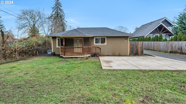 rear view of property featuring a wooden deck, a patio area, and a lawn