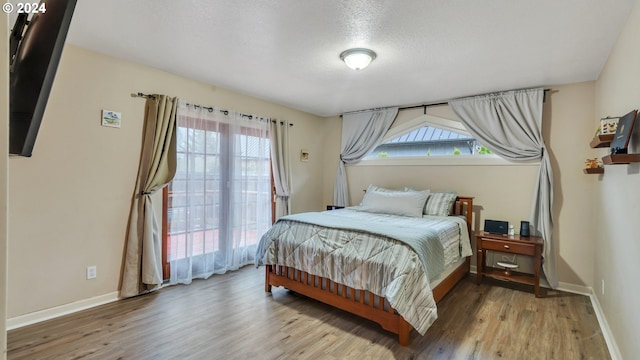 bedroom with multiple windows, light hardwood / wood-style flooring, and a textured ceiling