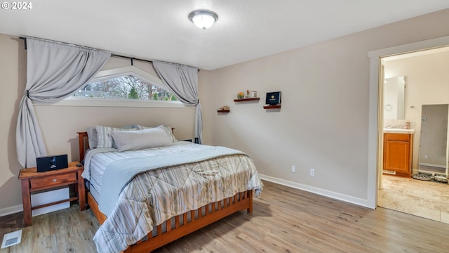 bedroom with ensuite bathroom and light hardwood / wood-style flooring