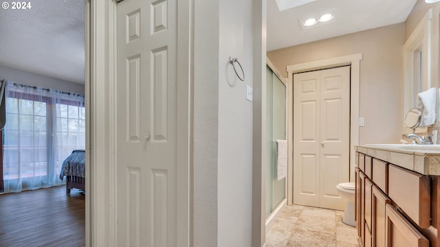 bathroom with hardwood / wood-style floors, vanity, toilet, and walk in shower