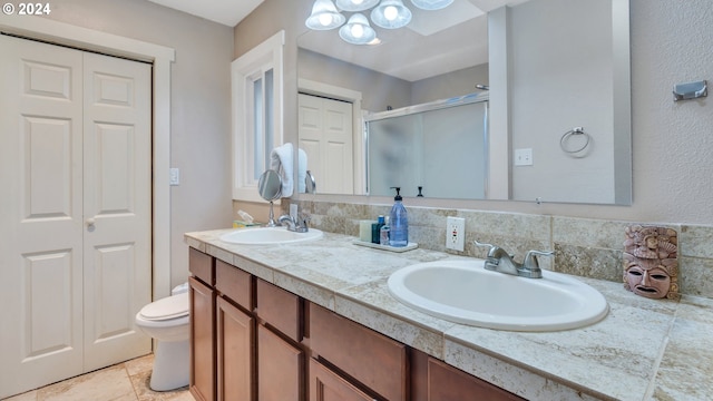 bathroom with a shower with door, vanity, and toilet