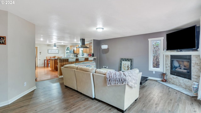 living room featuring ceiling fan, a fireplace, and light wood-type flooring